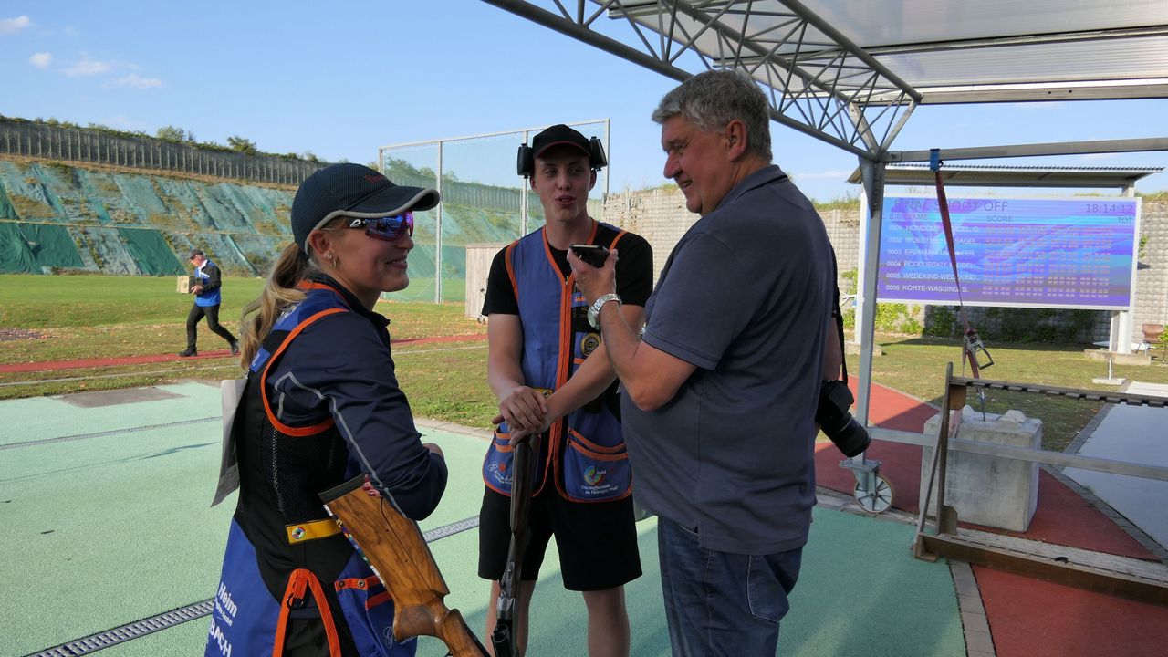 Foto: DSB / So kennt man Harald Strier: Fotokamera geschultert, Handy aufnahmebereit für Stimmenfang. Hier bei den Deutschen Meisterschaften mit dem Skeet-Duo Valentina Umhöfer und Magnus Erdmann.